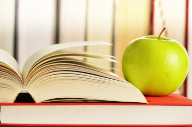 Composition with green apple and books on the table
