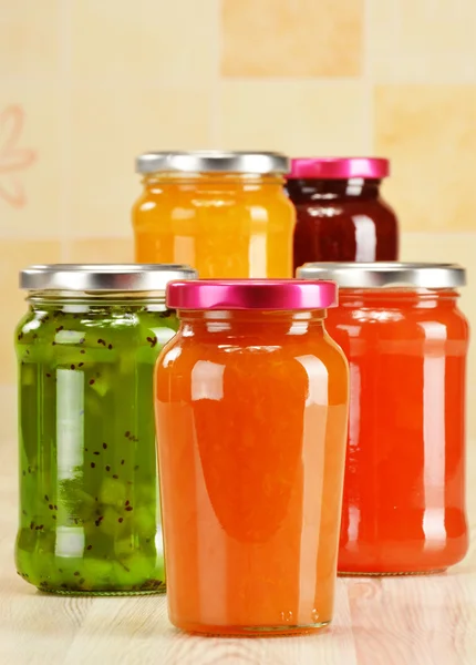 Jars of fruity jams on kitchen table. Preserved fruits — Stock Photo, Image