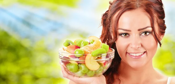 Young woman holding glass bowl with fruit salad — Stock Photo, Image