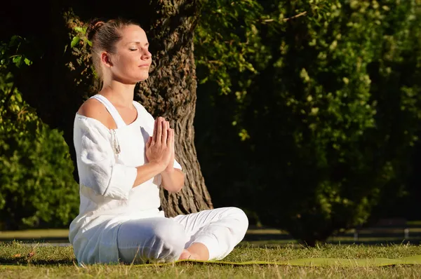 Молодая женщина во время медитации йоги в парке — стоковое фото