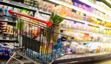 Süpermarkette market ürünleriyle dolu bir alışveriş arabası.