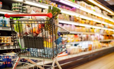 Süpermarkette market ürünleriyle dolu bir alışveriş arabası.