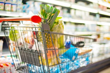 Süpermarkette market ürünleriyle dolu bir alışveriş arabası.