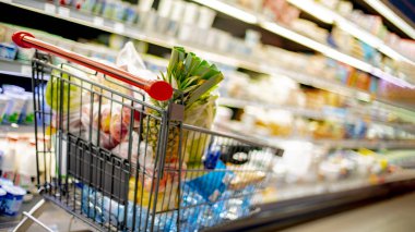 Süpermarkette market ürünleriyle dolu bir alışveriş arabası.