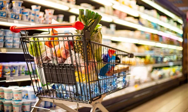 A shopping cart with grocery products in a supermarket