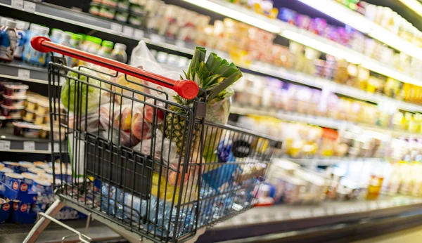 A shopping cart with grocery products in a supermarket