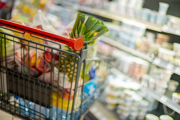 Süpermarkette market ürünleriyle dolu bir alışveriş arabası.