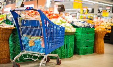 Süpermarkette market ürünleriyle dolu bir alışveriş arabası.