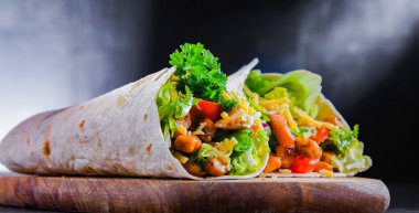 Kesme tahtasında tavuk ve taze sebzeli tortilla.