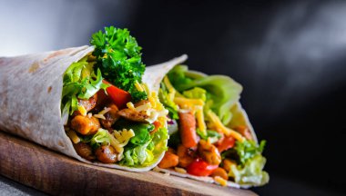 Kesme tahtasında tavuk ve taze sebzeli tortilla.