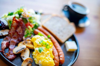 Çırpılmış yumurta, pastırma, sosis ve restoran masasında tost.