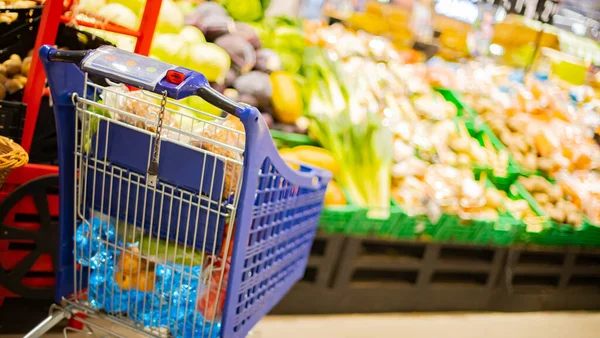 Süpermarkette market ürünleriyle dolu bir alışveriş arabası.