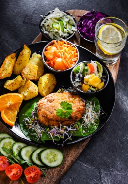 Patates ve sebze salatalı ekmek kırıntılarıyla kaplanmış tavuk pirzolası.
