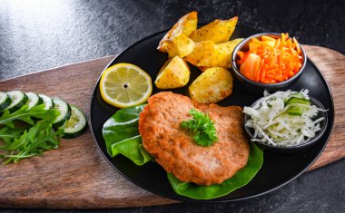 Patates ve sebze salatalı ekmek kırıntılarıyla kaplı domuz pirzolası.