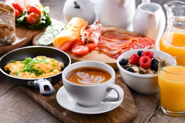 Kahvaltının yanında kahve, portakal suyu, omlet, tahıl, jambon ve peynir..