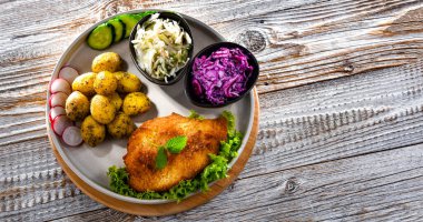 Patates ve sebze salatalı ekmek kırıntılarıyla kaplı domuz pirzolası.