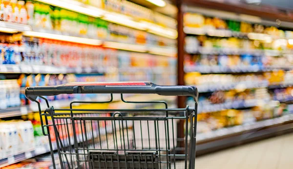 A shopping cart by a store shelf in a supermarket