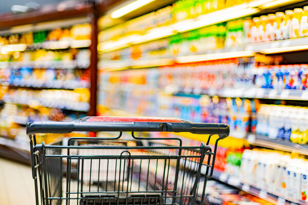 A shopping cart by a store shelf in a supermarket