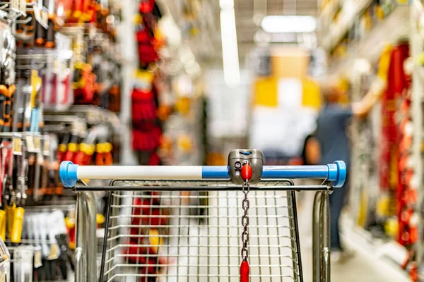 A shopping cart by a store shelf in a hardware store.