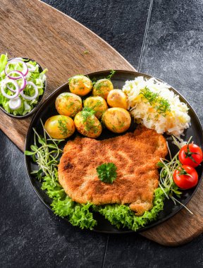 Patates ve lahana ile servis edilen ekmek kırıntılarıyla kaplı domuz pirzolası.