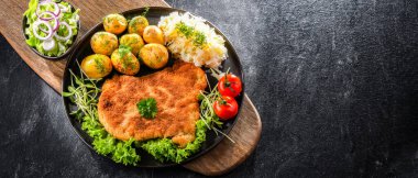 Patates ve lahana ile servis edilen ekmek kırıntılarıyla kaplı domuz pirzolası.