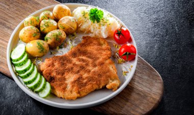 Patates ve lahana ile servis edilen ekmek kırıntılarıyla kaplı domuz pirzolası.
