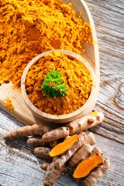 Bir kase zemin zerdeçal ve taze rhizomu ile kompozisyon.