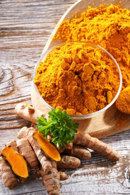 Bir kase zemin zerdeçal ve taze rhizomu ile kompozisyon.