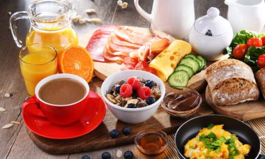 Kahvaltının yanında kahve, portakal suyu, omlet, tahıl, jambon ve peynir..