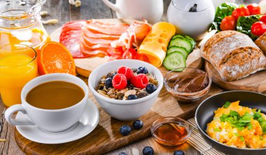 Kahvaltının yanında kahve, portakal suyu, omlet, tahıl, jambon ve peynir..