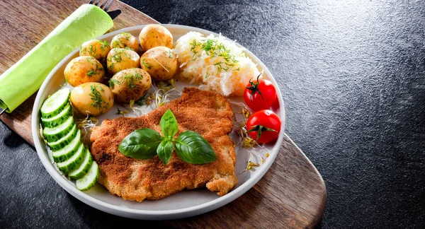 Pork breaded cutlet coated with breadcrumbs served with potatoes and cabbage