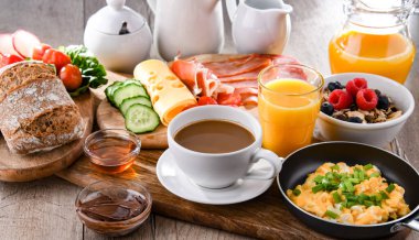 Kahvaltının yanında kahve, portakal suyu, omlet, tahıl, jambon ve peynir..