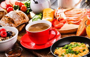 Kahvaltının yanında kahve, portakal suyu, omlet, tahıl, jambon ve peynir..