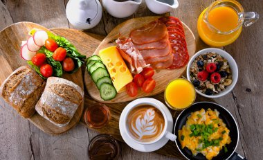 Kahvaltının yanında kahve, portakal suyu, omlet, tahıl, jambon ve peynir..