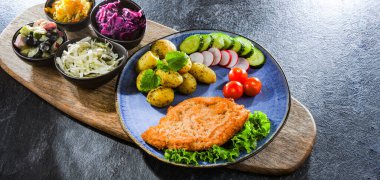 Patates ve sebze salatalı ekmek kırıntılarıyla kaplı domuz pirzolası.