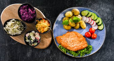 Patates ve sebze salatalı ekmek kırıntılarıyla kaplı domuz pirzolası.