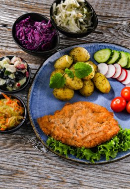 Patates ve sebze salatalı ekmek kırıntılarıyla kaplı domuz pirzolası.