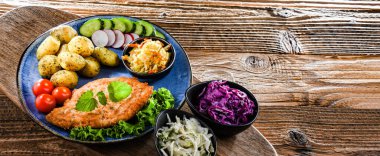 Patates ve sebze salatalı ekmek kırıntılarıyla kaplı domuz pirzolası.