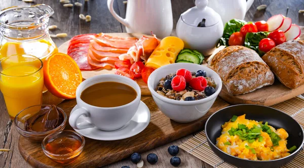 Kahvaltının yanında kahve, portakal suyu, omlet, tahıl, jambon ve peynir..