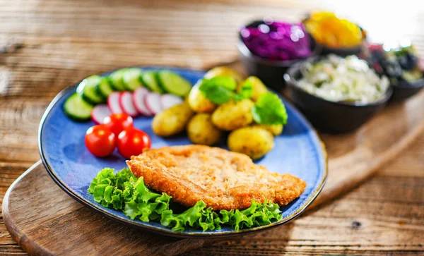 Pork breaded cutlet coated with breadcrumbs with potatoes and vegetable salads