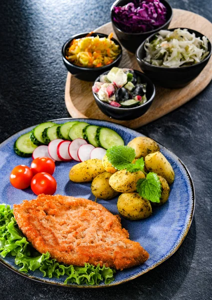 Patates ve sebze salatalı ekmek kırıntılarıyla kaplı domuz pirzolası.