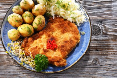 Patates ve lahana ile servis edilen ekmek kırıntılarıyla kaplı domuz pirzolası.