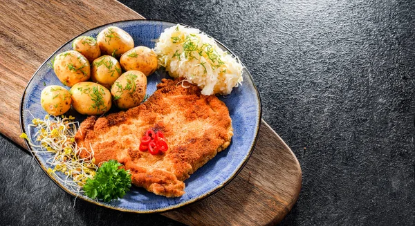 Pork breaded cutlet coated with breadcrumbs served with potatoes and cabbage