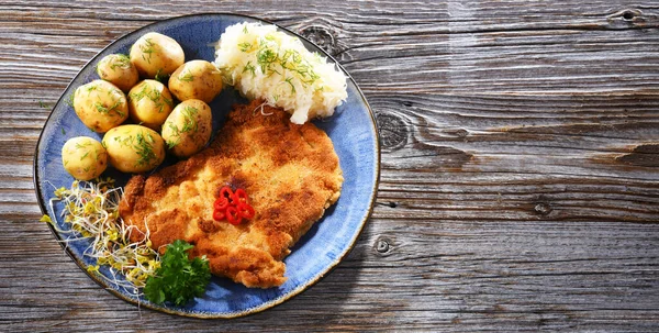 Pork breaded cutlet coated with breadcrumbs served with potatoes and cabbage