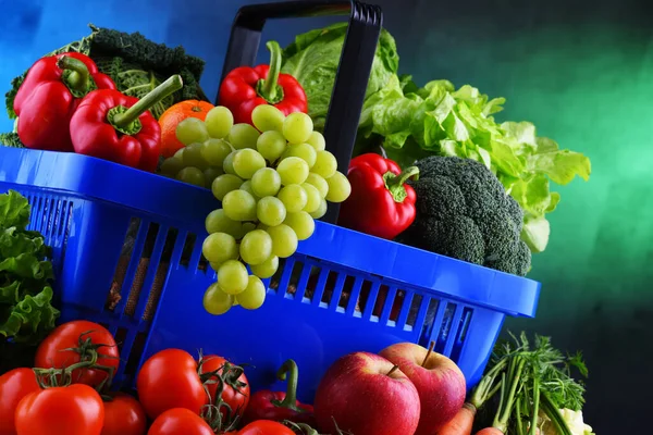 Fresh organic fruits and vegetables in plastic shopping basket.