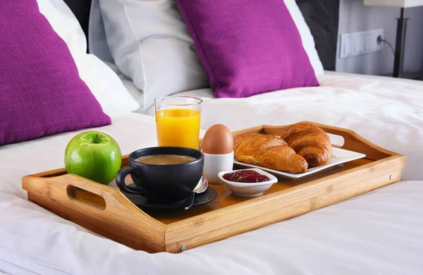 Breakfast on tray in bed in hotel room.