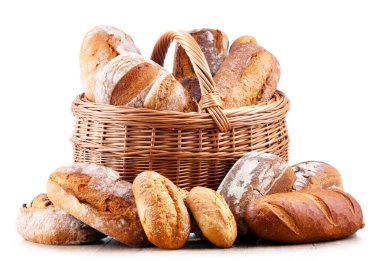 Wicker basket with assorted bakery products including loafs of bread and rolls over white background