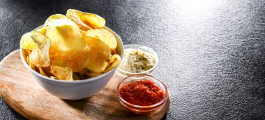 Bir kase patates cipsi ve soslu kompozisyon.