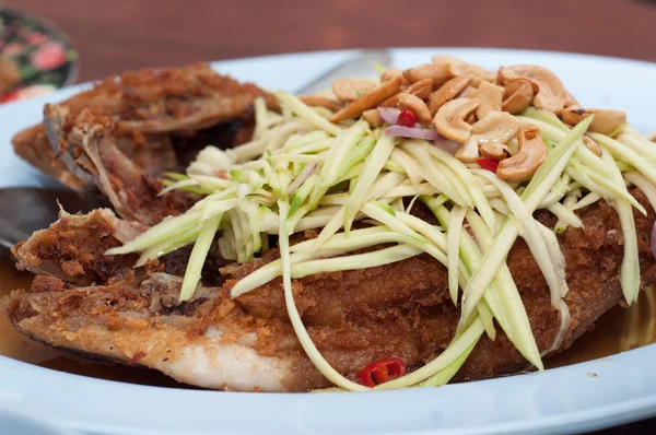 Fried fish with papaya and cashew on top — Stock Photo, Image