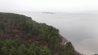 Karelia, Onega Gölü, Petrozavodsk Körfezi. Botanik bahçesinin yakınındaki ormanı ve sahili gösteren hava videosu. Gölün su yüzeyi ve sonbahar ormanı. Rusya 'da tatil kavramı.